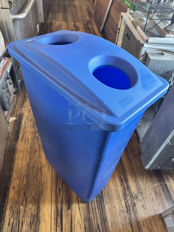 Blue 23-gallon slim recycling bin with dual circular openings, Rubbermaid logo, good condition. Ideal for space-saving waste management.