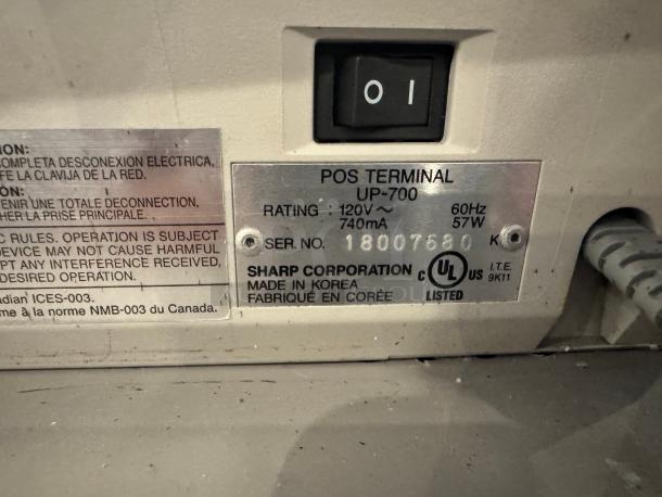 Sharp UP-700 POS terminal label showing model, 120V rating, and serial number 18007680. Made in Korea.