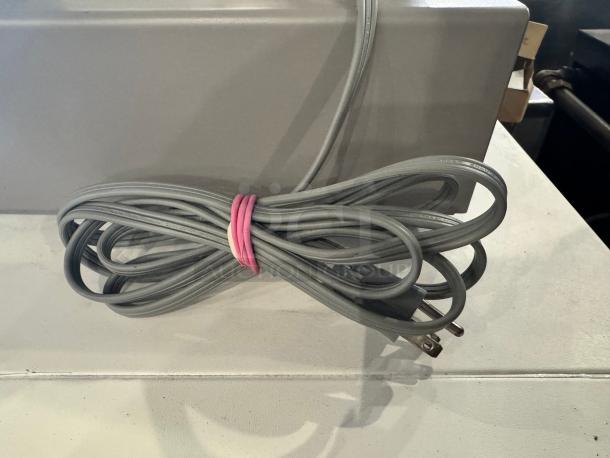 Sharp UP-700 POS terminal power cord, securely bundled, gray color, indicates standard compatibility and functionality.