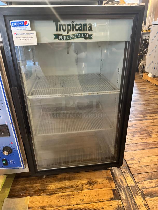 TRUE GDM-07 glass door cooler merchandiser with Tropicana branding, shelves visible, used condition, Pepsi repair label present.