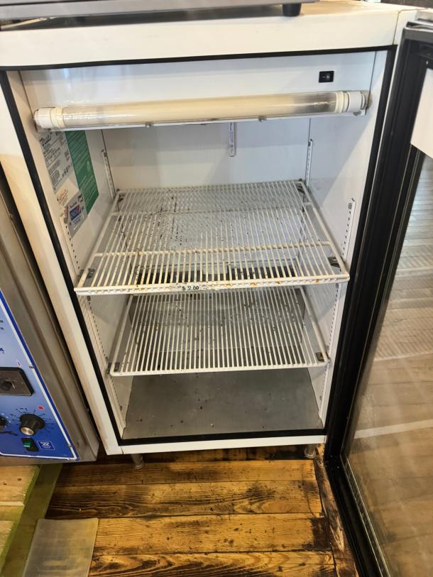 TRUE GDM-07 glass door cooler merchandiser, two shelves, visible wear, interior light, manufacturer labels present.