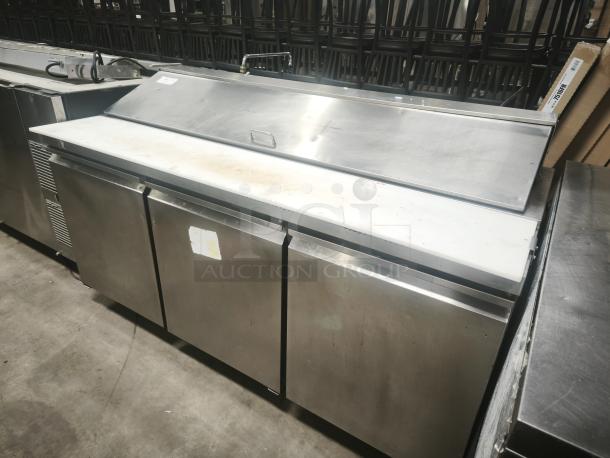 Heavy-duty 3-door refrigerated sandwich prep table with stainless steel finish, showing signs of use.