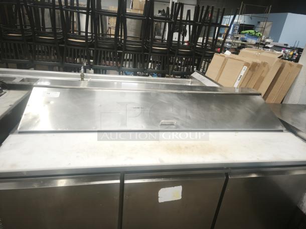 Heavy-duty 3-door refrigerated sandwich prep table, stainless steel, visible wear, with cutting board top.