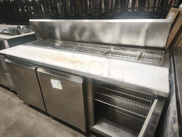 Heavy-duty 3-door refrigerated sandwich prep table, stainless steel, visible wear, interior shelves, open top lid.