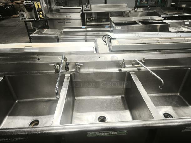 Heavy-duty 3-compartment stainless steel sink in good condition, featuring industrial-grade faucet and plumbing fixtures. Ideal for commercial use.