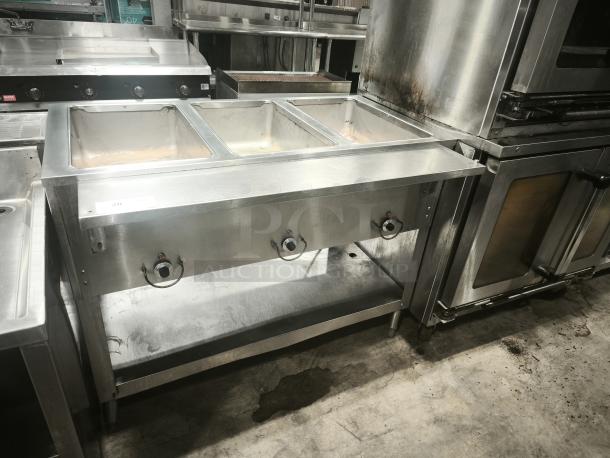 Commercial stainless steel heavy-duty steamer with three compartments, control knobs, and sturdy legs, in used condition.