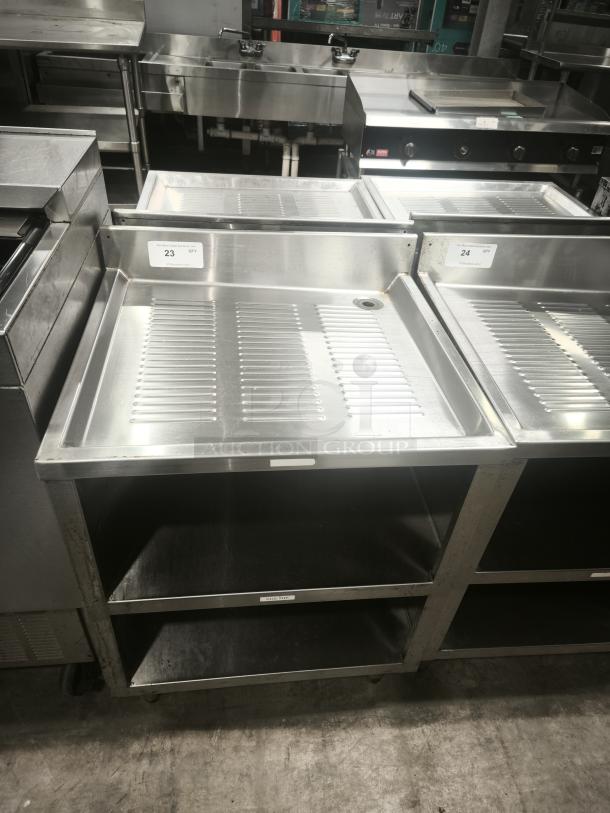 Heavy-duty stainless steel pan rack with two storage shelves and drainage feature, marked with quantity tags "23" and "24."