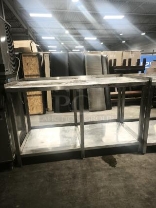 Stainless steel table with one shelf, industrial-style, good condition, visible wear on surface. Ideal for commercial use.