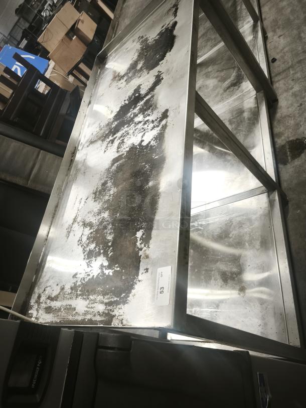 Stainless steel table with one shelf, showing signs of wear and rust. Features label marked "53 CTY."