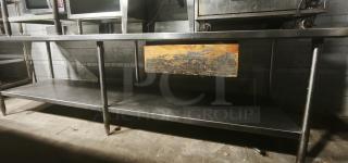 Stainless steel table with one shelf. Industrial style, slightly worn. Ideal for kitchen or workshop use. Sturdy design.