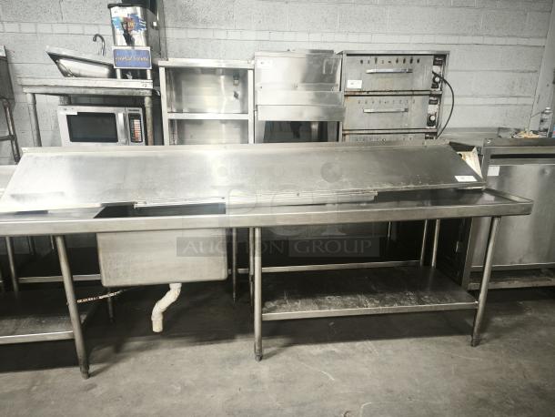 Stainless steel kitchen shelf with sink and storage, used condition. Includes work surface and lower shelf, suitable for commercial kitchens.