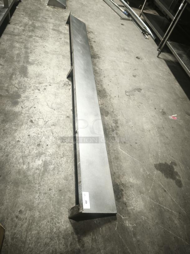 Stainless steel kitchen shelf, long design. Excellent condition with a visible label marked "002." Ideal for storage.