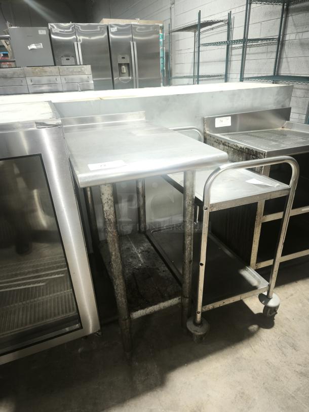 Heavy-duty small stainless steel prep table with visible wear. Features sturdy legs and a clean surface. Ideal for kitchen use.