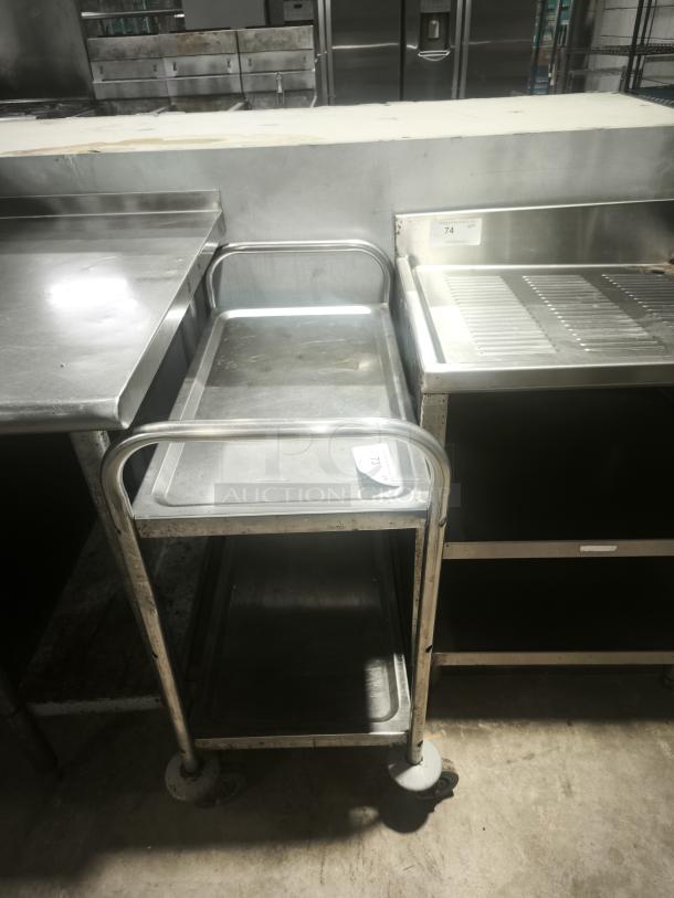 Heavy-duty small stainless steel prep table with two shelves, wheels, and a label marked "73." Sturdy condition.