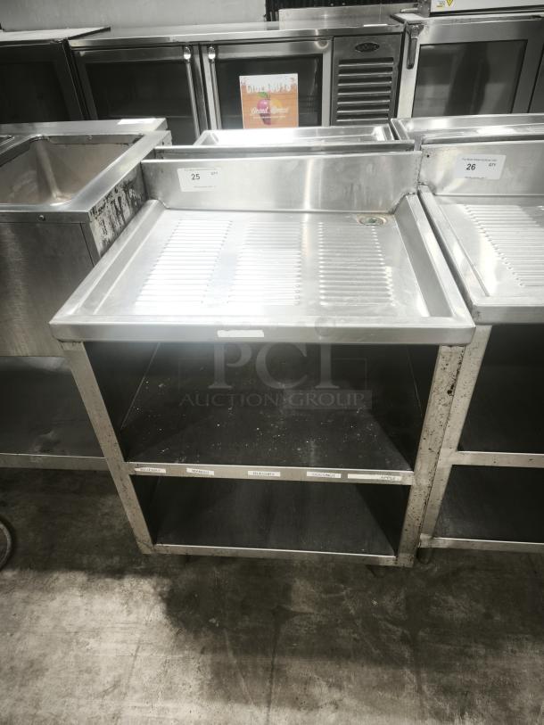 Heavy-duty stainless steel pan rack with two lower shelves, visible labels for organization, sturdy construction, used condition.