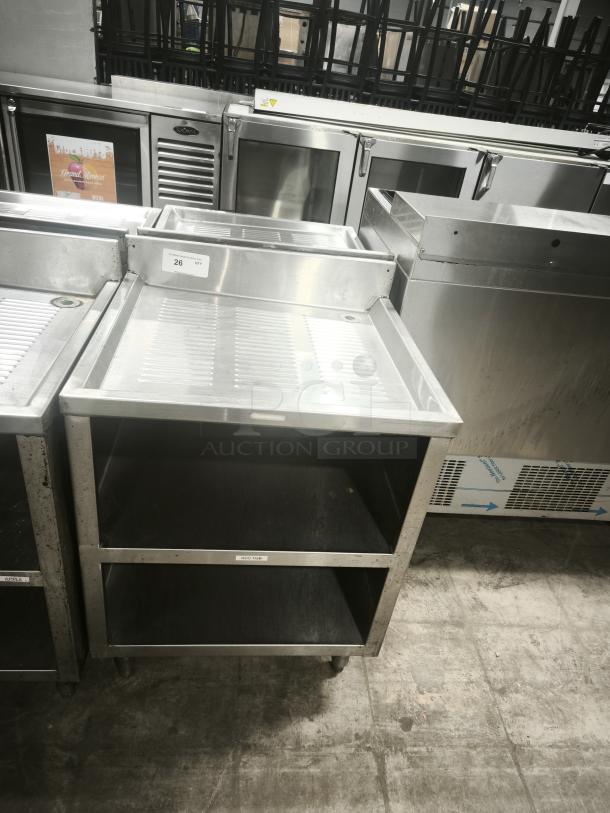 Heavy-duty underbar glass rack storage cabinet with drainboard top. Features two open shelves, stainless steel, good condition.
