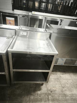 Heavy-duty underbar glass rack storage cabinet with drainboard top. Features two open shelves, stainless steel, good condition.