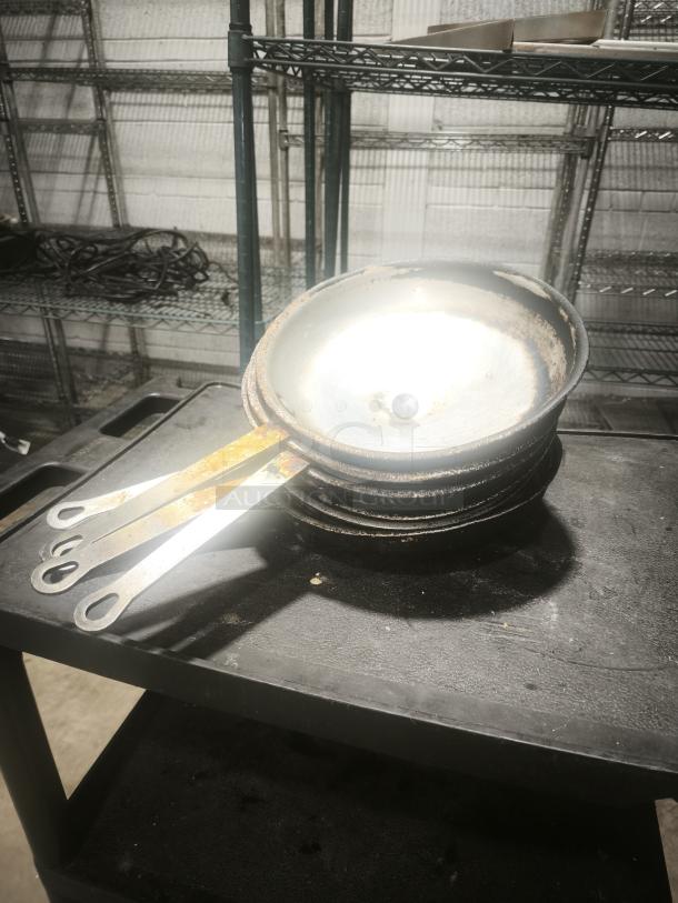 12" stainless clad frying pan with slightly worn surface, visible stacking wear, located on a metal shelf.