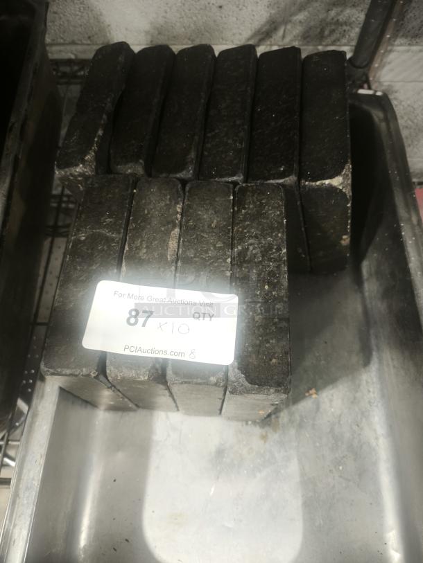 Heavy-duty metal weights, rectangular, stacked in a tray. Auction label reads "87 x 10 QTY PCIauctions.com".