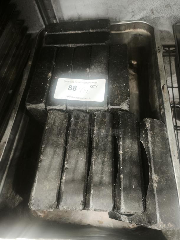 Heavy-duty metal ingots stacked in a tray, showing signs of wear. Label indicates quantity as 88.
