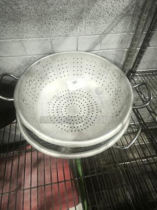 Heavy aluminum colander with handles and round base, showing slight wear. Quantity label visible.