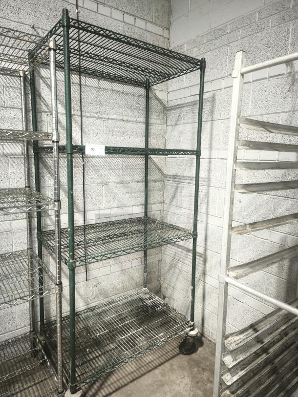 Green epoxy wire shelf with four tiers, in good condition. Features sturdy metal construction and caster wheels for mobility.