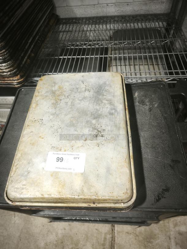 Aluminum cake baking pan with visible wear, rectangular shape, and a sticker labeled "99" from PCIAuctions.com.
