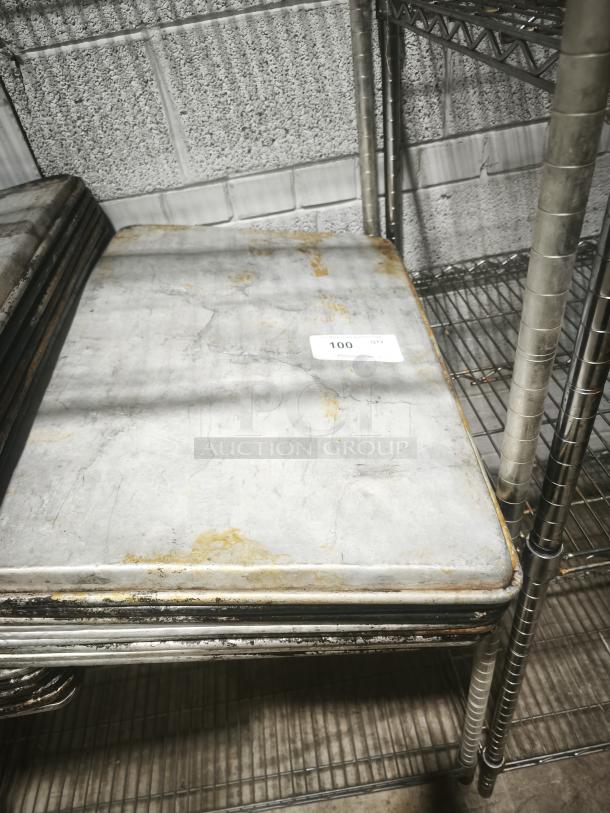 Aluminum cake baking pan with visible wear, stacked on metal shelving. Marked "100 QTY" on a label.