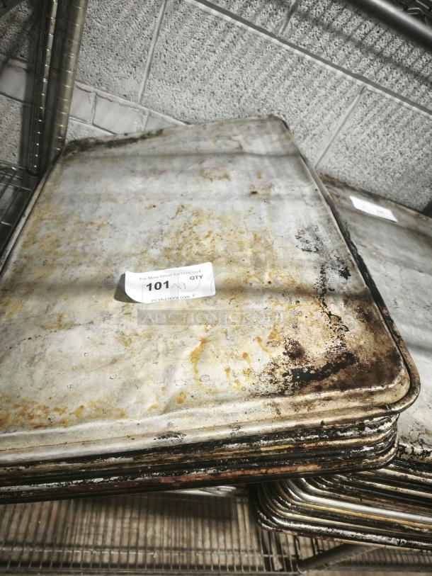 Stack of used aluminum cake baking pans with noticeable wear and rusting. Auction tag visible, labeled "101."