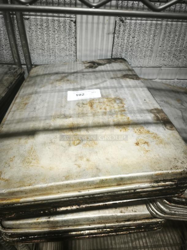 Stack of aluminum cake baking pans with visible wear and rust, featuring a label marked "102."