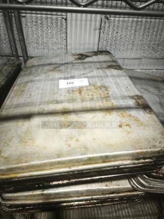 Stack of aluminum cake baking pans with visible wear and rust, featuring a label marked "102."