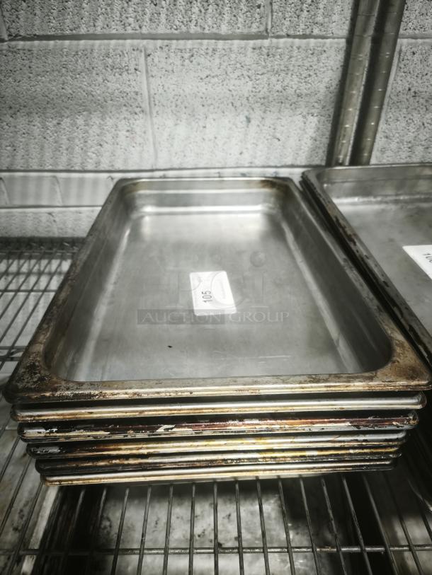 Full-size rectangular food pans, stacked, showing use and wear. Includes visible sticker label with text "105".