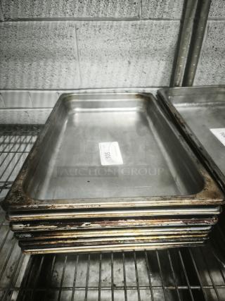 Full-size rectangular food pans, stacked, showing use and wear. Includes visible sticker label with text "105".