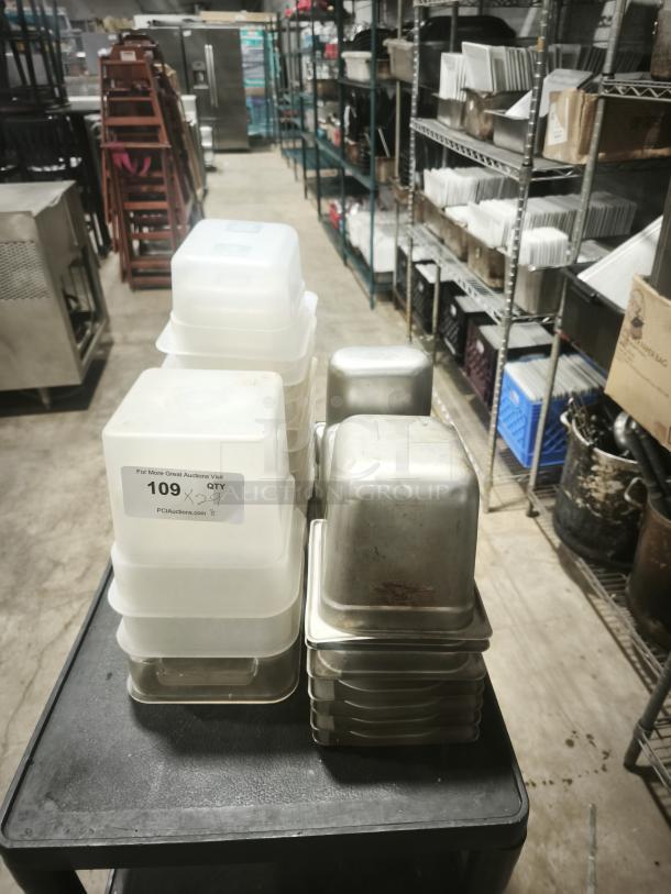 Various-sized food containers, plastic and stainless steel, stacked on a trolley. Label indicates "109 x 29" quantity.