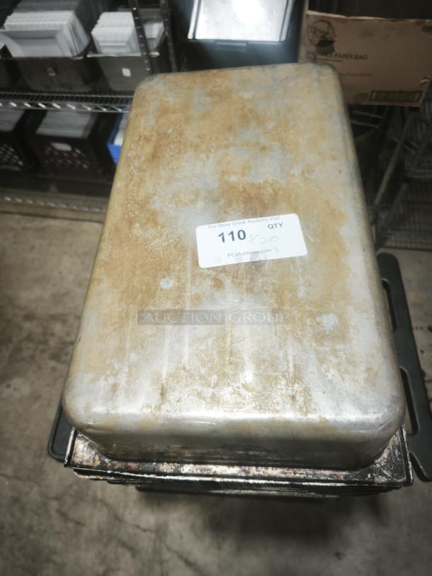 Stainless steel steam table pan, full size, 4" deep, visible wear, auction tag reads "110 x 30 QTY", stacked on rack.