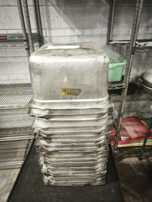 Stainless steel steam table pans, half full size, 6" deep, stacked; some wear evident, visible label with markings.