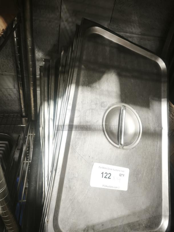 Stainless steel full-size pan lids with handles, stacked. Visible sticker: "122 QTY 14," referencing auction details.