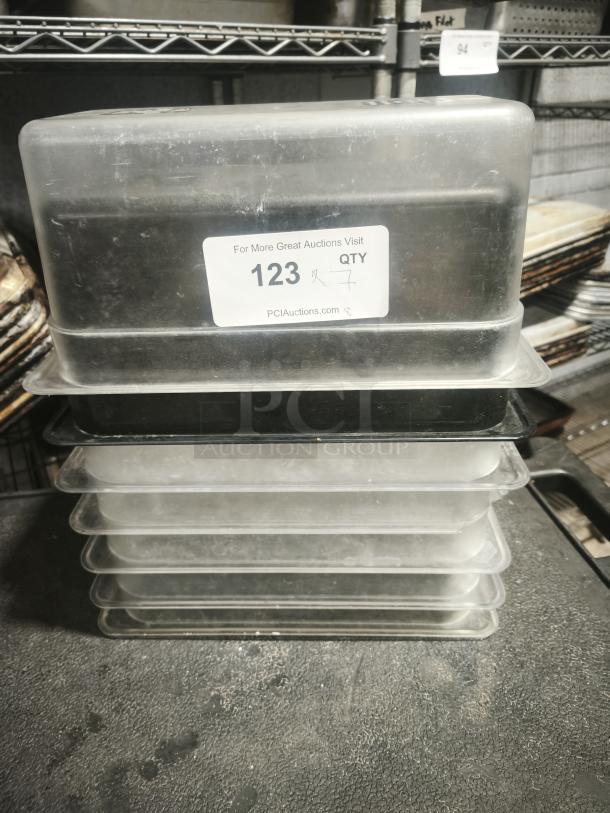 Stack of 1/3 full size pans in used condition, plastic material. Label indicates item number 123.