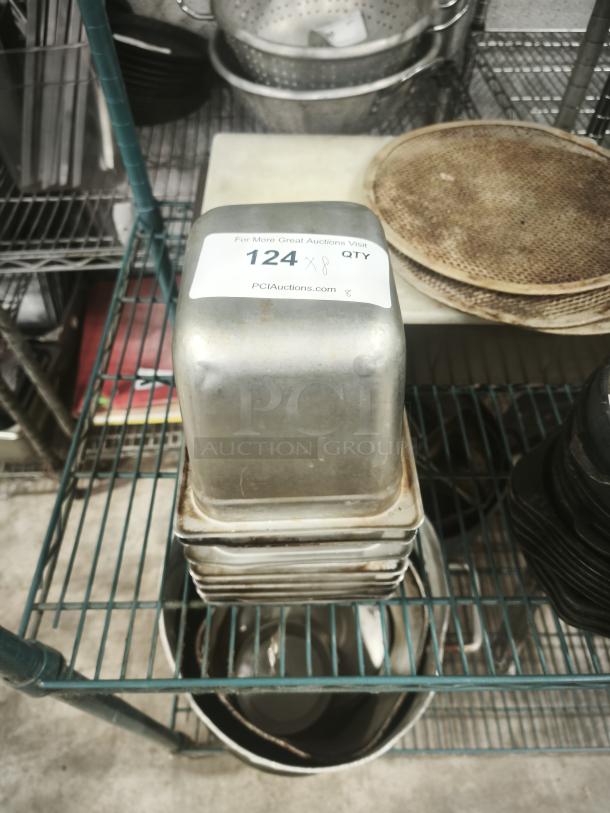 Stack of 1/4 full-size pans on a shelf, with visible label reading "124 x 8 QTY" for auction reference.