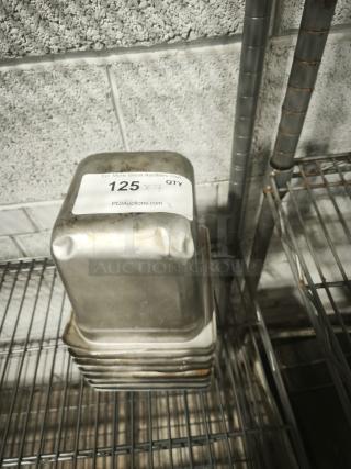 Stack of 1/4 full size pans on a wire rack, showing moderate wear. Visible label indicates auction lot number 125.