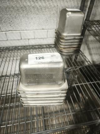 Stack of 1/9 size, 4" deep stainless steel food pans on a metal shelf, condition used. Label displays "126 x 6 QTY."