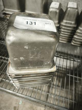 Steel 1/6 size 4" deep food pans, stack of nine, used condition, minor rust spots. Auction label "131" indicates quantity.