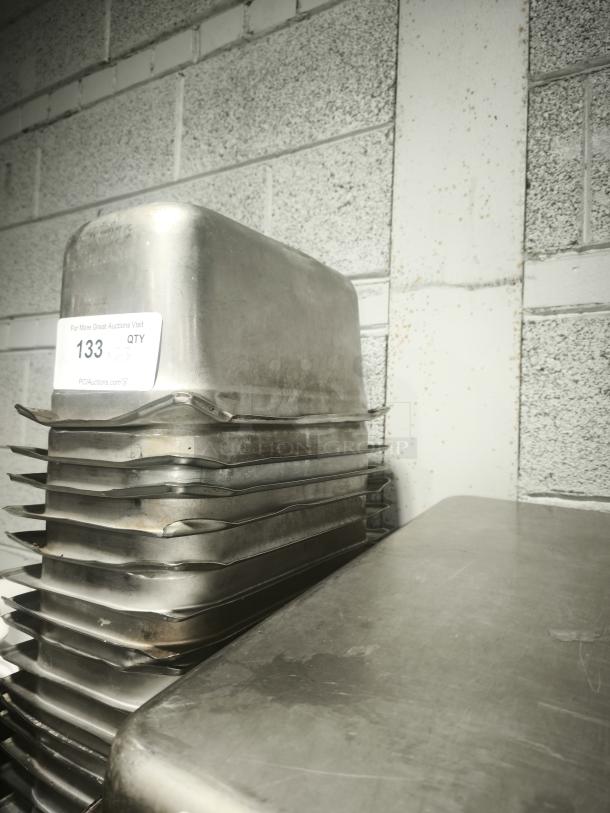 Stack of 1/3 size 4" deep stainless steel food pans, used condition, with auction label indicating lot number 133.