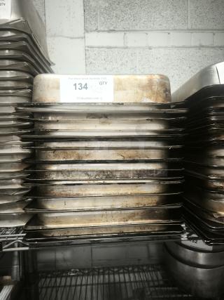 Stack of full size 4" deep food pans, used condition, with visible wear. Auction lot number 134 label on top pan.