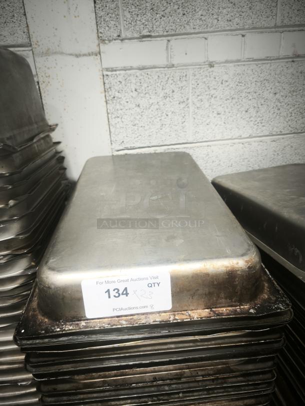 Full size 4" deep food pan in used condition, showing signs of wear. Stack of pans with auction tag "134" visible.