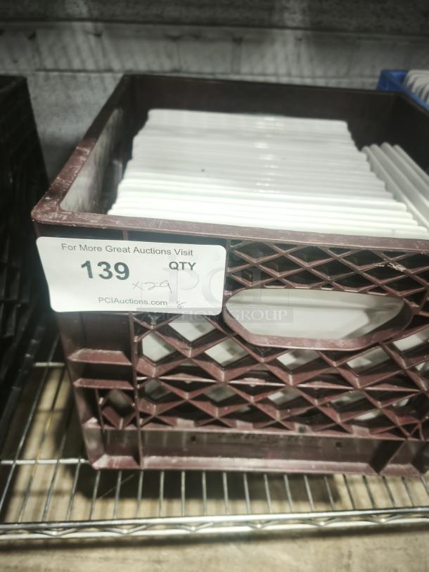 9" bright white square porcelain plates stacked in a brown crate. Excellent condition, ideal for dining presentation.