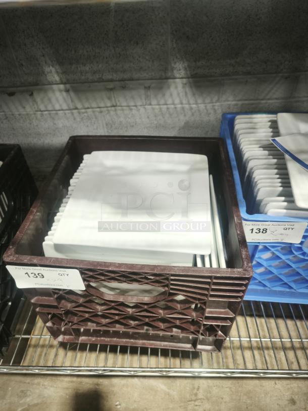 9" bright white square porcelain plates stacked in a crate. Plates appear in excellent condition. Auction tag reads "139 QTY."