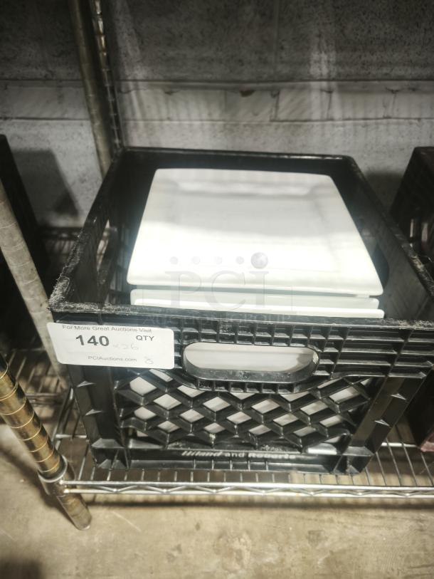 9" bright white square porcelain plate in excellent condition, stacked in a plastic crate. Label shows "Qty 26". Ideal for auctions.