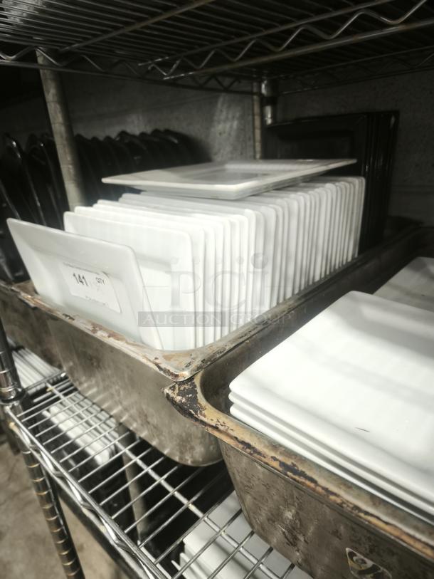 Stack of 9" bright white square porcelain plates on metal shelf, excellent condition, ideal for dinner presentation.