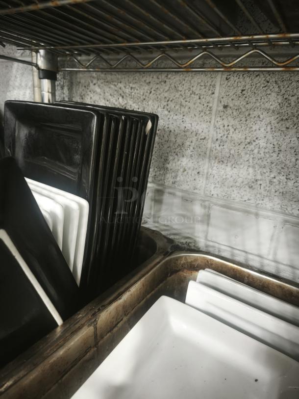 Matte black rectangular stoneware platters stacked vertically; sleek design, modern look, good condition.